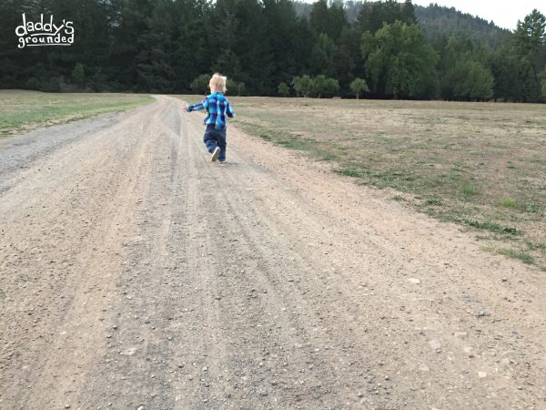 Toddler running on country road.
